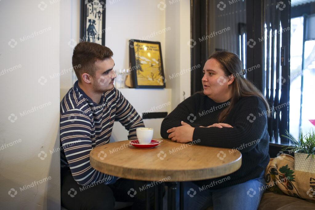 Two people sitting and talking indoors at a cafe – Mindframe online ...