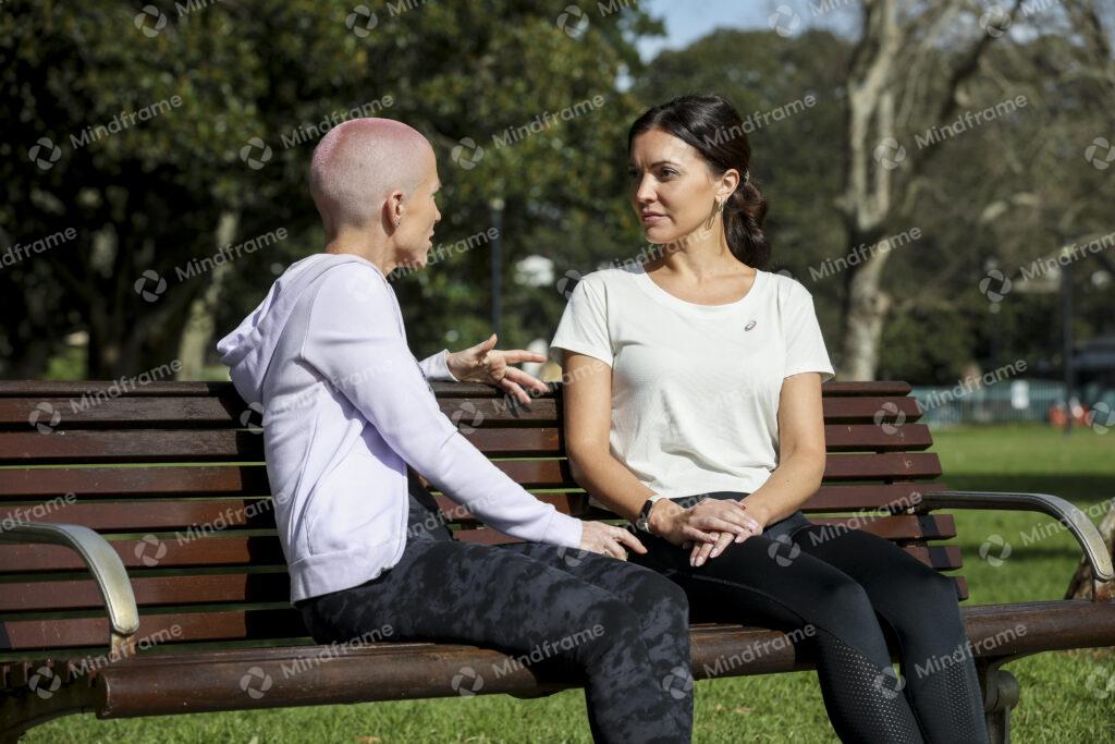 Two people sitting on a park bench, talking – Mindframe online image ...