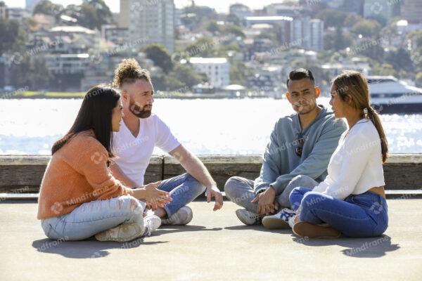 Four people sitting and talking near the water