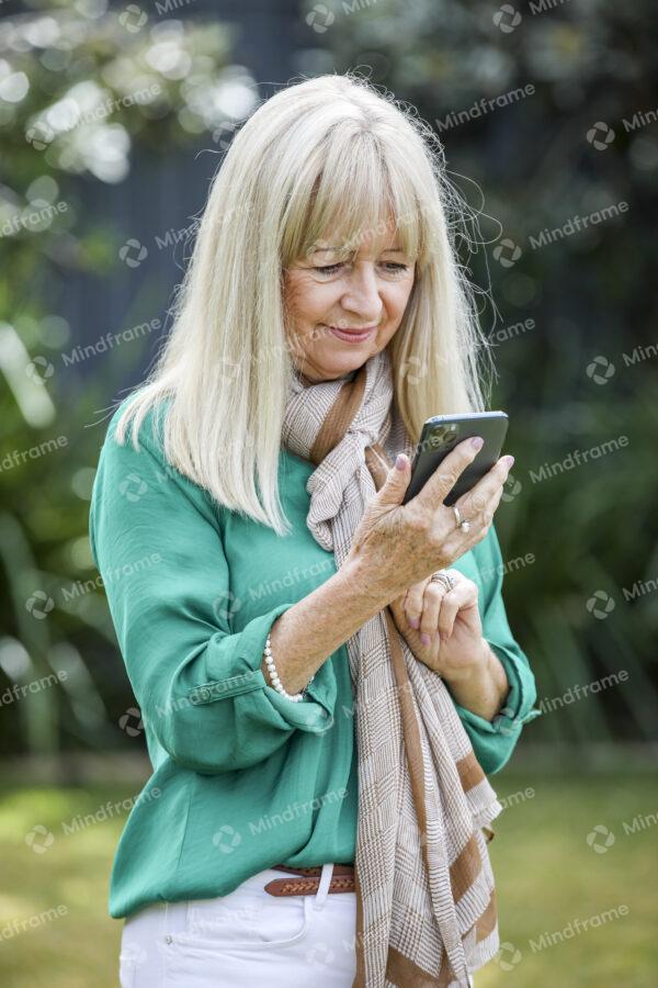 One person in the garden, on their phone, smiling