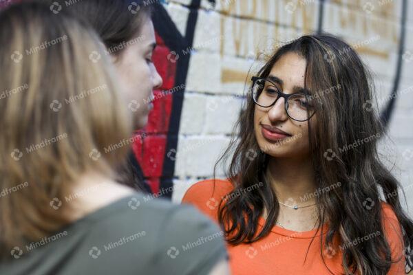 Group of young women standing outside by brick wall talking