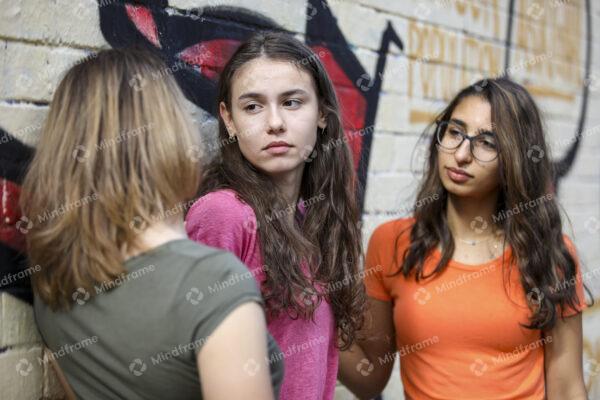 Group of young women standing outside by brick wall talking