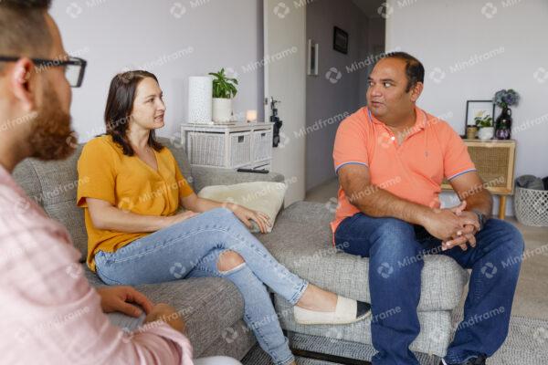 Three people talking and sitting on couch at home