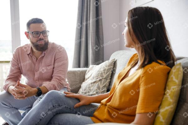 Two people talking and sitting on couch at home